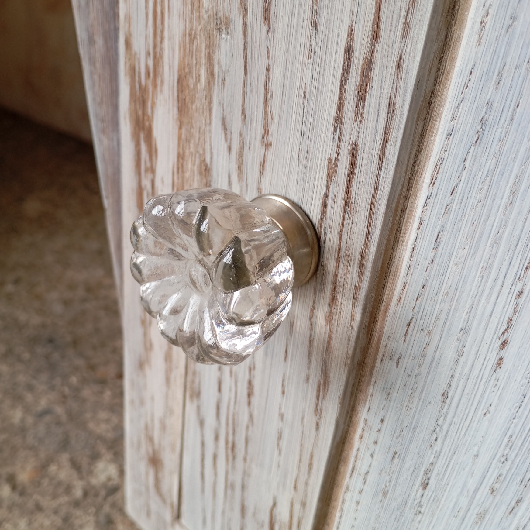 Vue du détail du bouton de porte d'un chevet style art déco avec marbre gris dessin fleur et céruse blanche