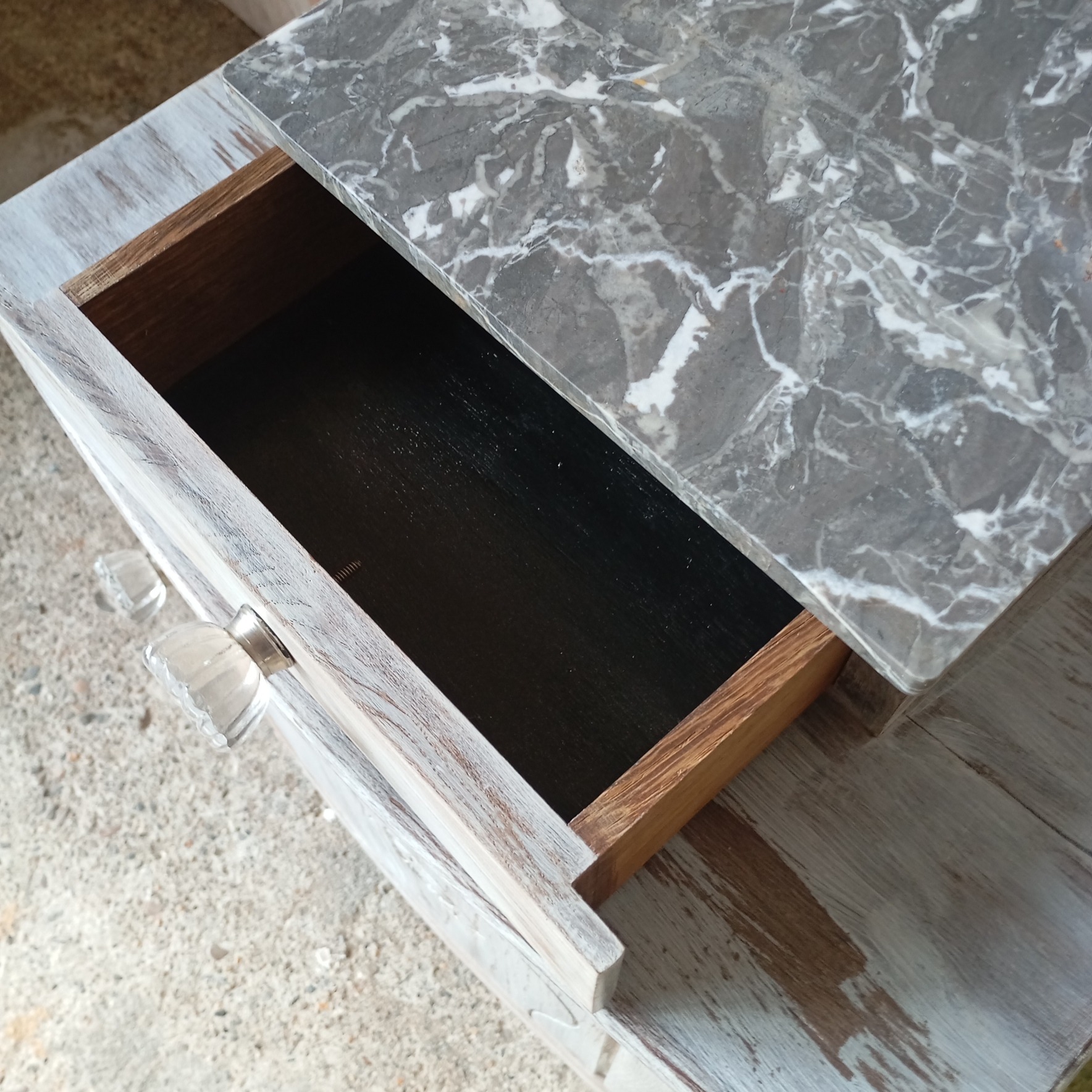 Vue du tiroir peint en noir d'un chevet style art déco avec marbre gris dessin fleur et céruse blanche